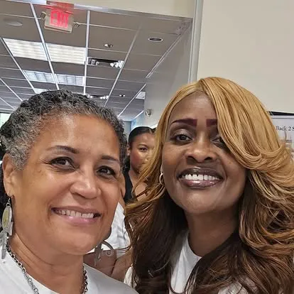 Two smiling women taking a selfie together in a retail or commercial indoor setting